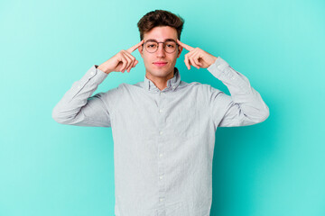 Young caucasian man isolated on blue background focused on a task, keeping forefingers pointing...