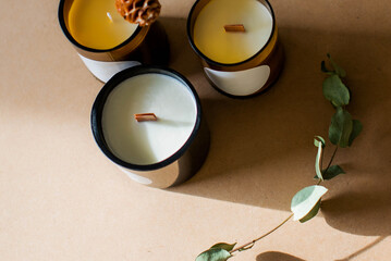 wooden wick candles. Handmade candle from paraffin and soy wax in glass with flowers and leaf on craft background. Let flay. Candle making. Top view.