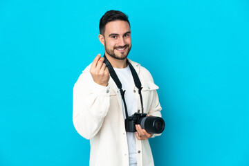 Young photographer man isolated on blue background making money gesture