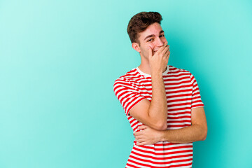 Young caucasian man isolated on blue background laughing happy, carefree, natural emotion.