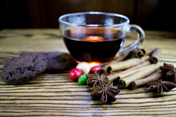 image of a cup of tea, anise, cinnamon, chocolate chip cookies and sweets on a wooden table