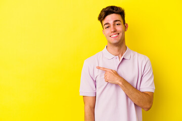 Young caucasian man isolated on yellow background smiling and pointing aside, showing something at blank space.