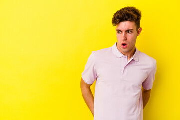 Young caucasian man isolated on yellow background being shocked because of something she has seen.