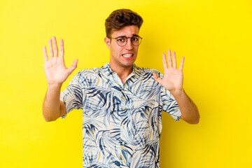 Young caucasian man isolated on yellow background rejecting someone showing a gesture of disgust.