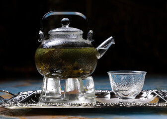 glass teapot and a cup of green tea