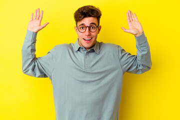 Young caucasian man isolated on yellow background receiving a pleasant surprise, excited and...