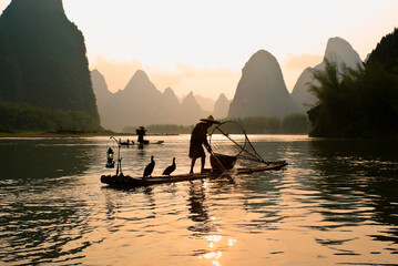 Cormorant fishermen on the Li River (Lijiang) with karst peaks in the background at sunset, near Xingping, Guangxi Province, China