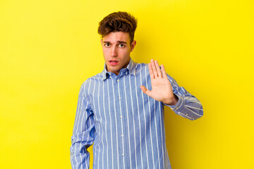 Young caucasian man isolated on yellow background being shocked due to an imminent danger