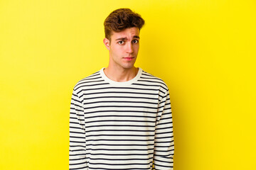 Young caucasian man isolated on yellow background sad, serious face, feeling miserable and displeased.