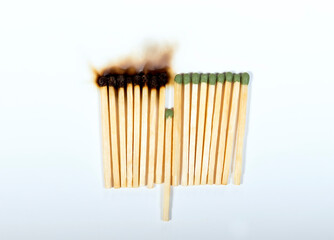 Burnt matches and whole matches on a white background. One whole match to stop the fire. Concept