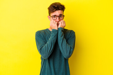 Obraz premium Young caucasian man isolated on yellow background biting fingernails, nervous and very anxious.