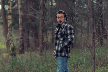 Cool man in checkered coat in the woods.