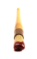 Wooden Culinary Brush Dipped in Barbecue Sauce on a White Background