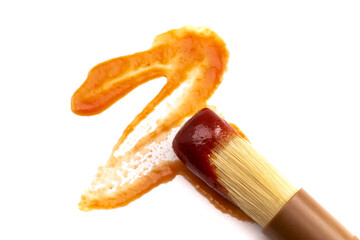 Wooden Culinary Brush Dipped in Barbecue Sauce on a White Background