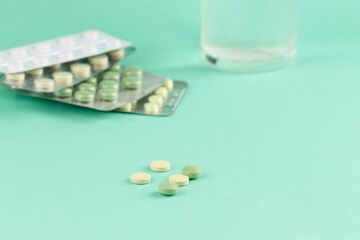 Pills and a glass of water on a green background. Medication.