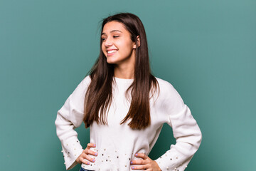 Young Indian woman isolated on blue background laughs happily and has fun keeping hands on stomach.
