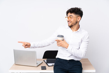 Arabian man in a office isolated on white background pointing finger to the side and presenting a product