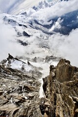 Obraz premium The mountain ranges are covered with snow and clouds. Snowy mountain peaks on a sunny winter day. Scenic Mountain landscape from the top of the mountain. Climbing mountain summits among the clouds.