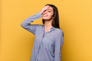 Young Indian woman isolated on yellow background laughing happy, carefree, natural emotion.