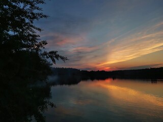 sunset over the lake in the summer with orange clouds