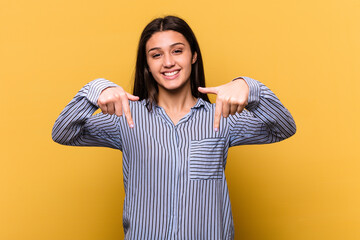 Young Indian woman isolated on yellow background points down with fingers, positive feeling. © Asier