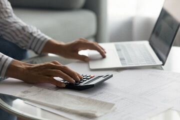 Close up woman using laptop and calculator, planning managing budget, businesswoman calculating bills, expenses, browsing online banking service, sitting at table with financial documents and receipt