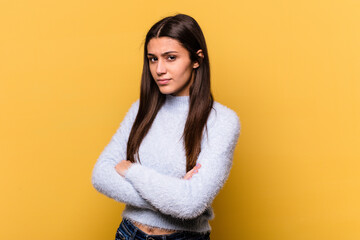 Young Indian woman isolated on yellow background suspicious, uncertain, examining you.
