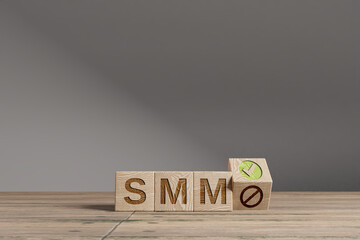 Wood cubes with acronym 'SMM' on a beautiful wooden table, studio background. Business concept and copy space.