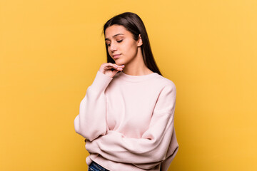 Obraz premium Young Indian woman isolated on yellow background looking sideways with doubtful and skeptical expression.