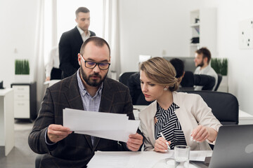 A young Manager gives paper documents to the head of the HR Department in the office of the leasing company for verification