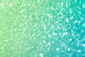 Sparkling abstract light green background. Bright gradient glitter with blur effect. Holiday abstraction close-up