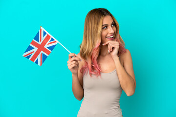 Young woman holding an United Kingdom flag over isolated blue background thinking an idea and looking side