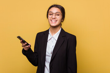 Young indian business woman talking on phone isolated on yellow background