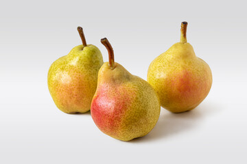 Three fresh yellow-red pears on a light background