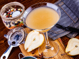 Pear cocktail in martini glass on wooden table. Close up