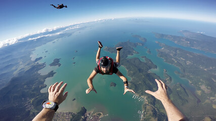 A group of parachuting friends jumping over the sea. First person view. - 422178003
