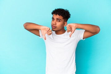 Young african american curly man isolated on blue showing thumb down, disappointment concept.