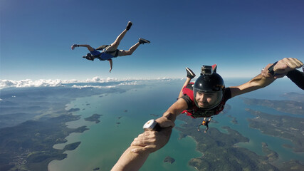 A group of parachuting friends jumping over the sea. First person view.