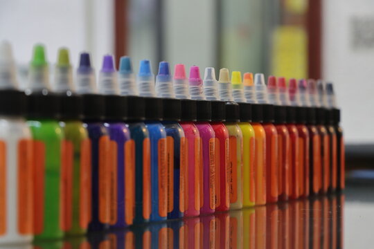 Tintas de colores en envases de plástico formadas en una fila y fondo bokeh