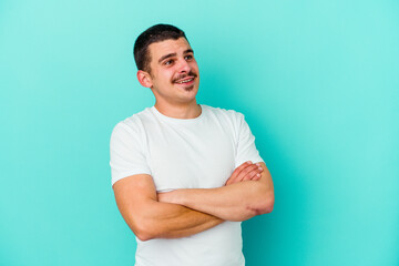 Young caucasian man isolated on blue background dreaming of achieving goals and purposes