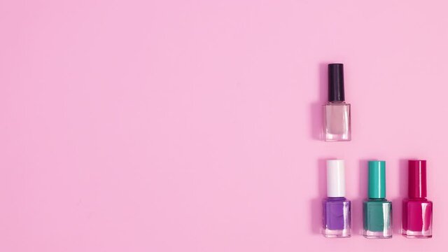 Manicure tools and nail polish bottles appear on bright pink background. Creative layout of manicure tools. Stop motion flay lay