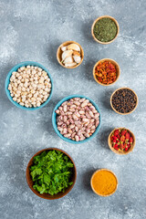 Fototapeta na wymiar Blue bowls of raw beans and spices on marble background