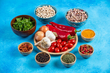 Plate of vegetables, beans and spices on blue background