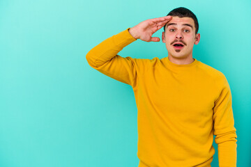 Fototapeta premium Young caucasian man isolated on blue background looking far away keeping hand on forehead.