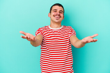 Young caucasian man isolated on blue background makes scale with arms, feels happy and confident.