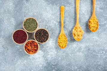 Various dry pasta and spices on marble background