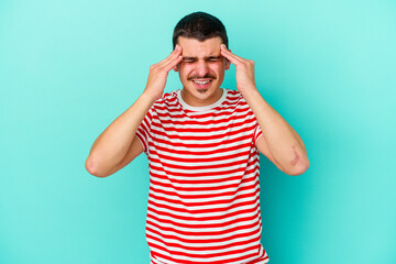 Young caucasian man isolated on blue background having a head ache, touching front of the face.