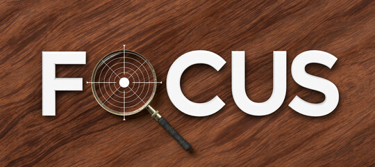 Focus concept with white text and magnifying glass in place of letter O over a target or bulls eye in a conceptual image on a panorama wood background.