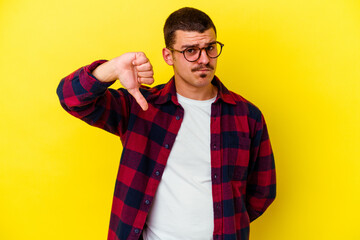 Young caucasian cool man isolated on yellow background showing thumb down, disappointment concept.
