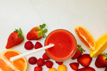 Red smoothie in a glass next to apricot, strawberries, grapefruit and raspberries. Red juice from fresh fruits. Healthy juice for breakfast.	